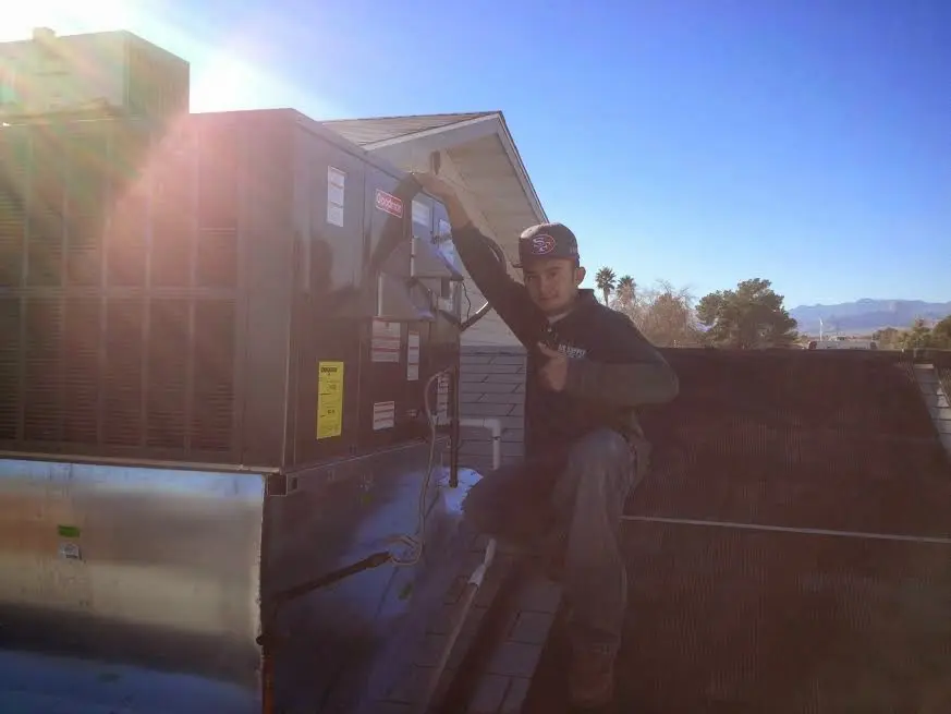 HVAC technician performing Air Duct Cleaning on a rooftop unit in Austin